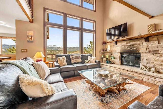 living room with beam ceiling, a wealth of natural light, a fireplace, and hardwood / wood-style flooring