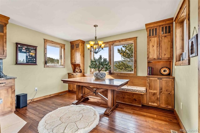 dining area featuring a healthy amount of sunlight, dark hardwood / wood-style floors, and a notable chandelier