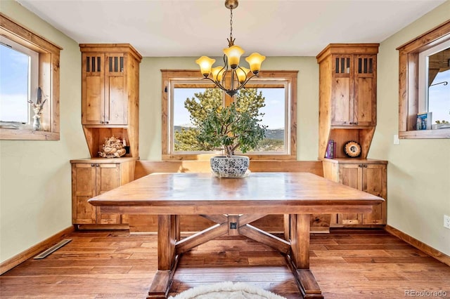 unfurnished dining area with plenty of natural light, a notable chandelier, and light wood-type flooring