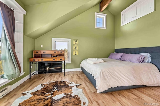 bedroom featuring multiple windows, light hardwood / wood-style flooring, a baseboard heating unit, and vaulted ceiling with beams