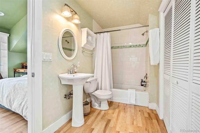 bathroom with hardwood / wood-style flooring, shower / bath combination with curtain, and toilet