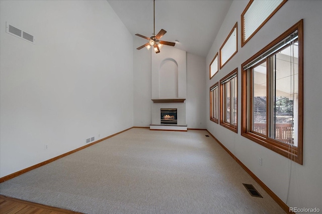 unfurnished living room featuring high vaulted ceiling, visible vents, and a glass covered fireplace