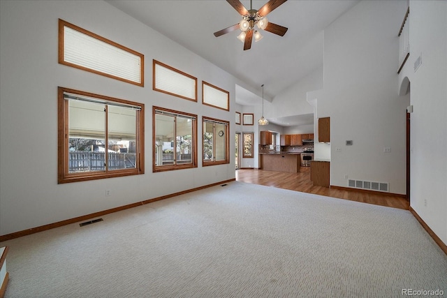 unfurnished living room featuring a wealth of natural light, visible vents, and light colored carpet