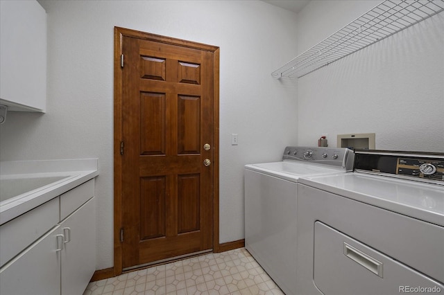 clothes washing area with light floors, independent washer and dryer, cabinet space, and baseboards