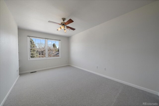 carpeted empty room with visible vents, ceiling fan, and baseboards