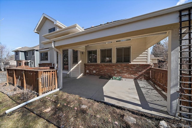 rear view of property with a patio area, brick siding, and fence