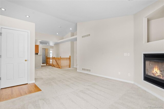 2951 S Walden Ct, Aurora, CO 80013 - unfurnished living room with lofted ceiling, light colored carpet, recessed lighting, a glass covered fireplace, and baseboards