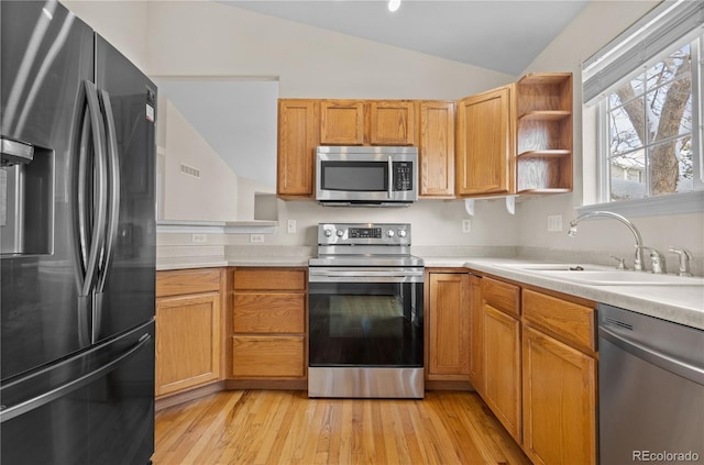 kitchen with stainless steel appliances, light hardwood / wood-style floors, sink, and vaulted ceiling