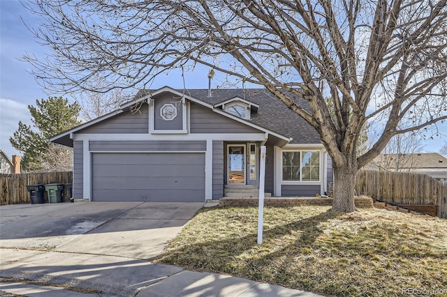 traditional-style home featuring a garage, roof with shingles, driveway, and fence