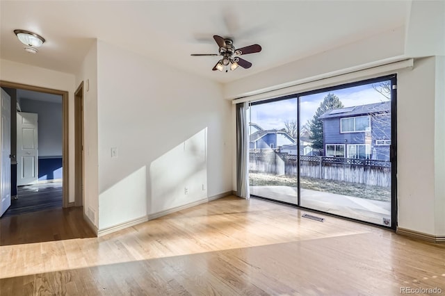 empty room with ceiling fan, visible vents, baseboards, and wood finished floors