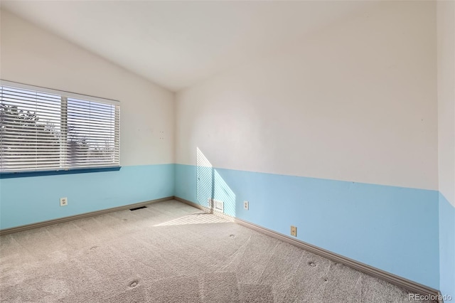 carpeted spare room with baseboards, lofted ceiling, and visible vents