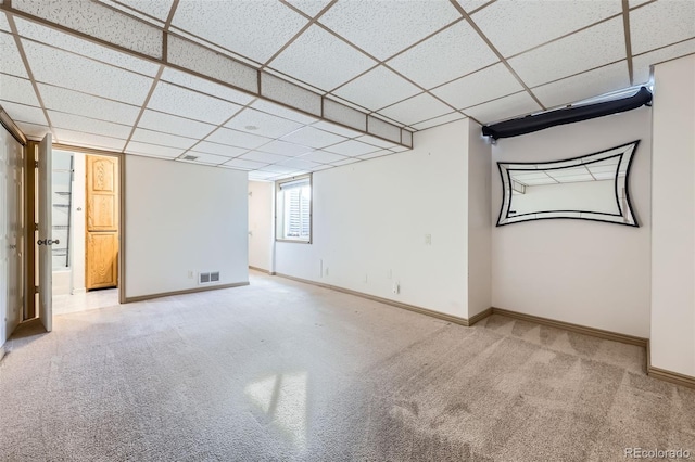 below grade area with a paneled ceiling, visible vents, baseboards, and carpet flooring