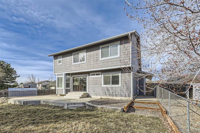 back of property with entry steps, a patio, a fenced backyard, and a lawn