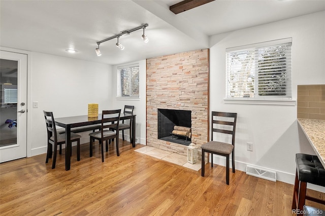 dining area with a fireplace, rail lighting, and light wood-type flooring