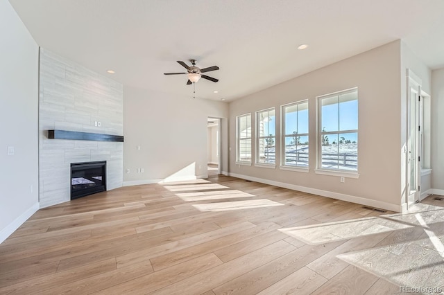 unfurnished living room with a tile fireplace, ceiling fan, and light hardwood / wood-style floors