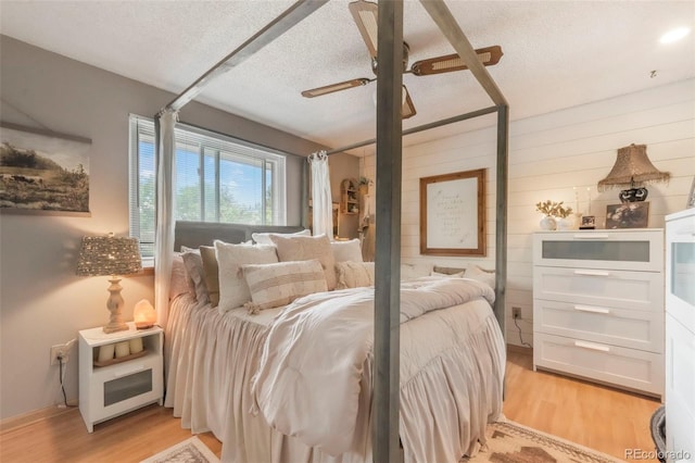 8280 Everett Way, Arvada, CO 80005 - bedroom with light wood-style floors, a textured ceiling, wooden walls, and a ceiling fan