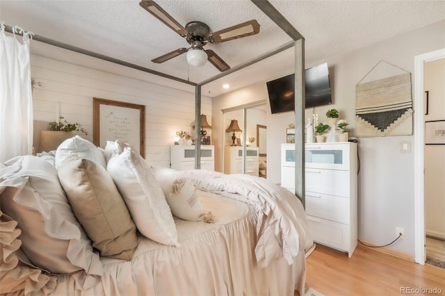8280 Everett Way, Arvada, CO 80005 - bedroom with a textured ceiling, light wood-style floors, a ceiling fan, and wooden walls