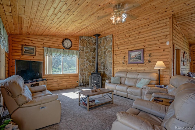 carpeted living room featuring a wood stove, vaulted ceiling, ceiling fan, and wooden ceiling