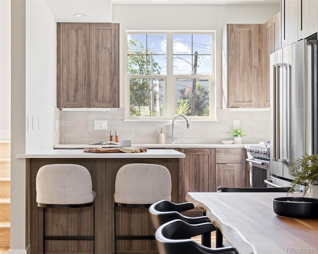 kitchen featuring high quality appliances, a kitchen breakfast bar, and decorative backsplash