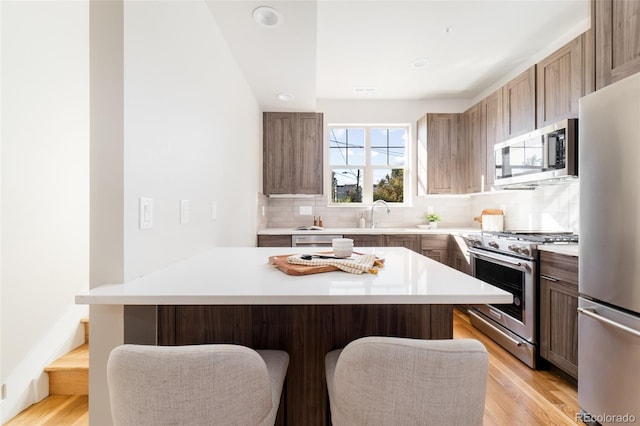 kitchen featuring appliances with stainless steel finishes, a breakfast bar area, a kitchen island, and backsplash