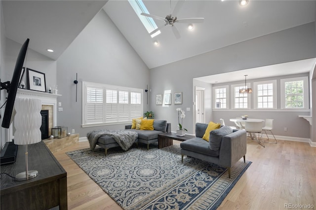 8721 E 23rd Ave, Denver, CO 80238 - living area featuring high vaulted ceiling, a fireplace with raised hearth, ceiling fan, light wood finished floors, and baseboards