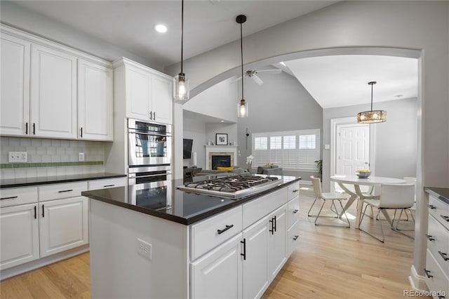 8721 E 23rd Ave, Denver, CO 80238 - kitchen with stainless steel appliances, light wood-style floors, dark countertops, a ceiling fan, and backsplash