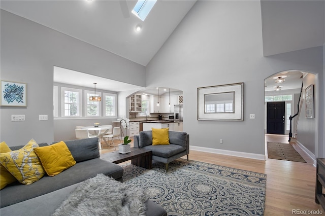 8721 E 23rd Ave, Denver, CO 80238 - living room featuring arched walkways, light wood-style floors, healthy amount of natural light, high vaulted ceiling, and baseboards