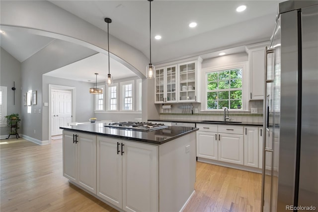 8721 E 23rd Ave, Denver, CO 80238 - kitchen featuring appliances with stainless steel finishes, light wood finished floors, dark countertops, white cabinetry, and healthy amount of natural light