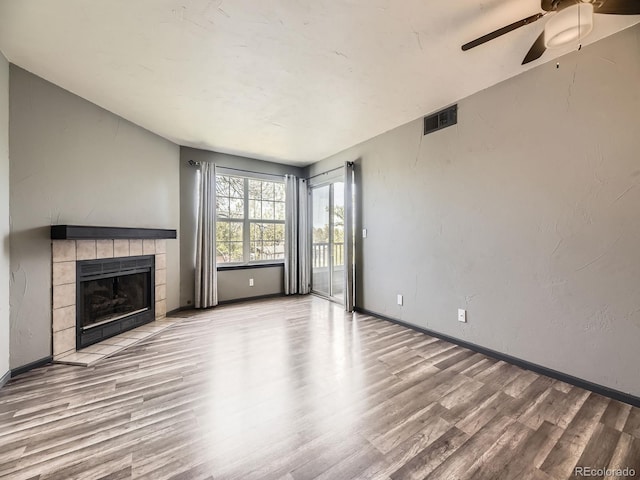 unfurnished living room featuring wood finished floors, ceiling fan, a fireplace, and baseboards