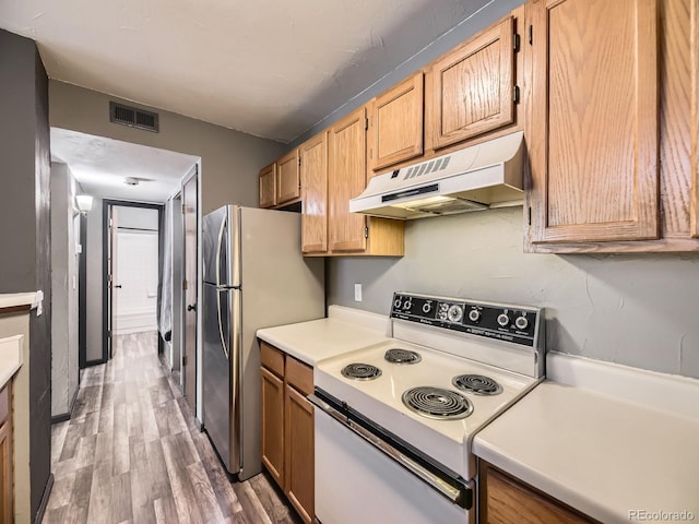 kitchen featuring white electric range, under cabinet range hood, wood finished floors, light countertops, and freestanding refrigerator