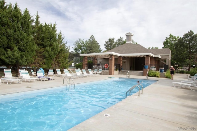 community pool with a patio and fence