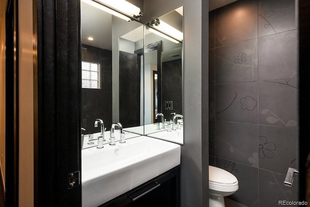 bathroom with tile walls, toilet, and vanity