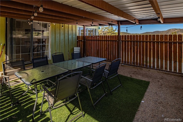 view of patio / terrace with outdoor dining space, fence, and a mountain view
