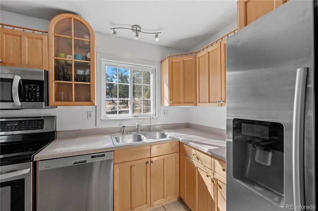kitchen with light brown cabinets, a sink, stainless steel appliances, light countertops, and glass insert cabinets