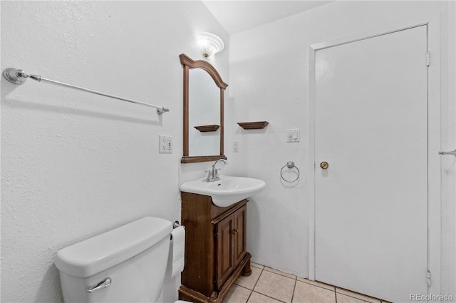 half bath featuring tile patterned floors, toilet, and vanity
