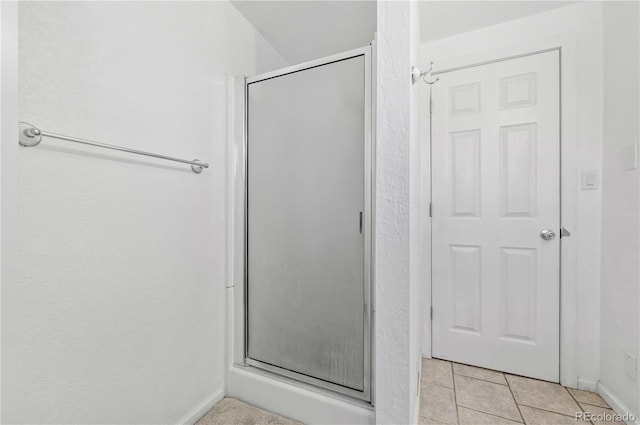 bathroom featuring tile patterned floors, a stall shower, and baseboards