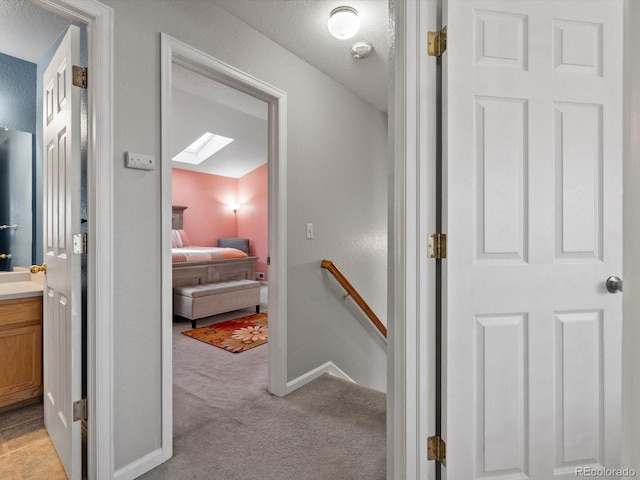 hall featuring light colored carpet and a skylight