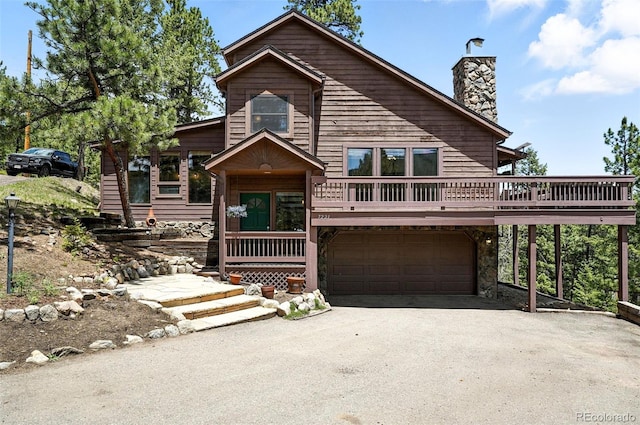 7221 S Brook Forest Rd, Evergreen, CO 80439 - chalet / cabin featuring driveway, a chimney, an attached garage, stone siding, and a wooden deck