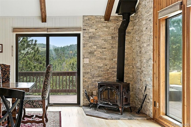 7221 S Brook Forest Rd, Evergreen, CO 80439 - doorway to outside with a wood stove, beamed ceiling, hardwood / wood-style floors, plenty of natural light, and wooden walls