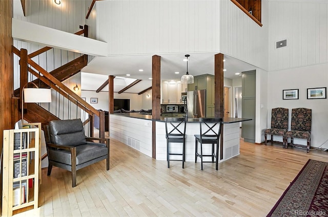 7221 S Brook Forest Rd, Evergreen, CO 80439 - kitchen featuring high end fridge, light wood-type flooring, dark countertops, a breakfast bar area, and a high ceiling