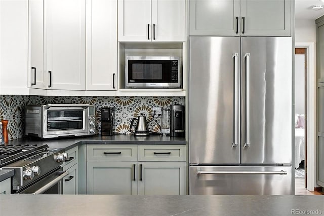 7221 S Brook Forest Rd, Evergreen, CO 80439 - kitchen featuring premium appliances, backsplash, dark countertops, and white cabinets