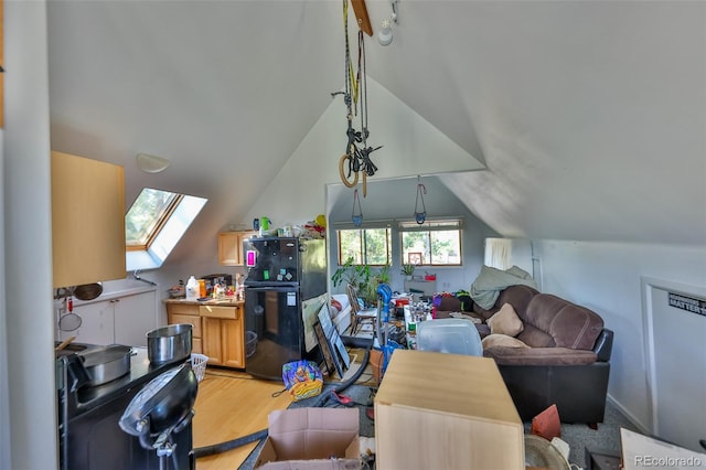 living room with vaulted ceiling with skylight and light hardwood / wood-style floors