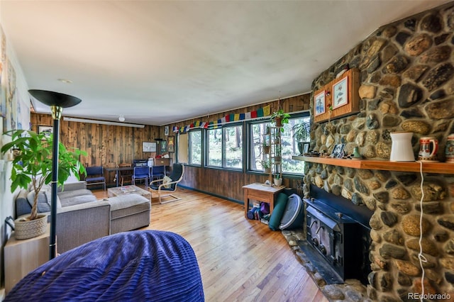 living room featuring wood-type flooring, wooden walls, and a fireplace