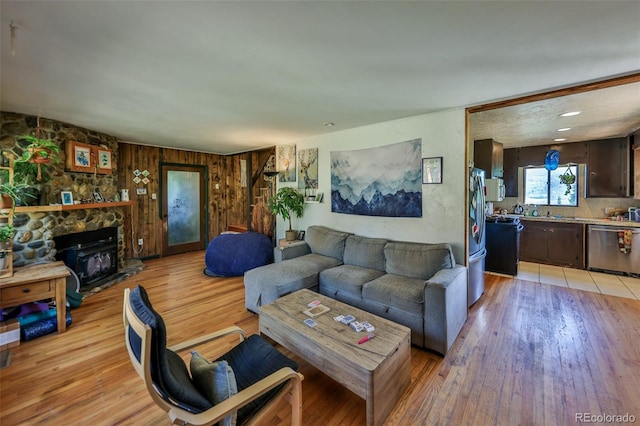 living room with wooden walls, a fireplace, and light hardwood / wood-style flooring