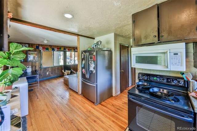 kitchen with light wood-type flooring, stainless steel fridge, black electric range, wood walls, and a textured ceiling