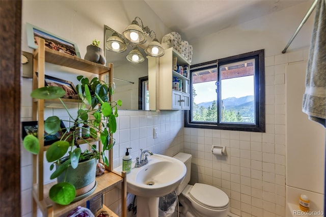 bathroom featuring a mountain view, walk in shower, tile walls, toilet, and sink