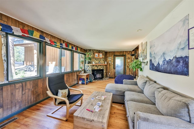 living room with wood-type flooring, wooden walls, and a fireplace