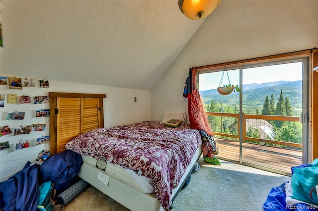 carpeted bedroom with lofted ceiling, a mountain view, and a textured ceiling