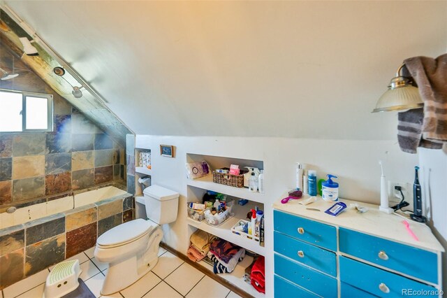 bathroom featuring lofted ceiling, toilet, a bathtub, and tile patterned floors