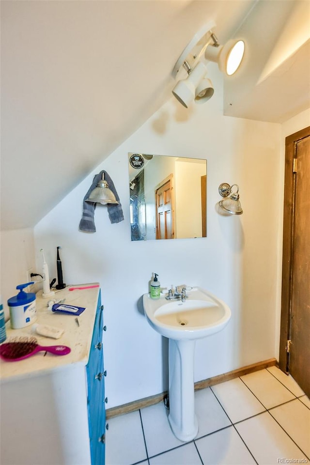 bathroom with vaulted ceiling, sink, and tile patterned floors